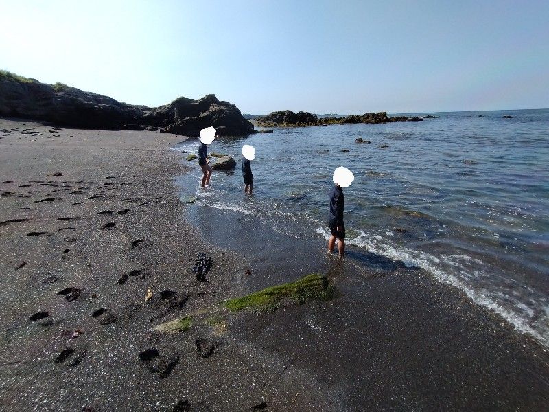 波打ち際で足をひたしている３人のこども